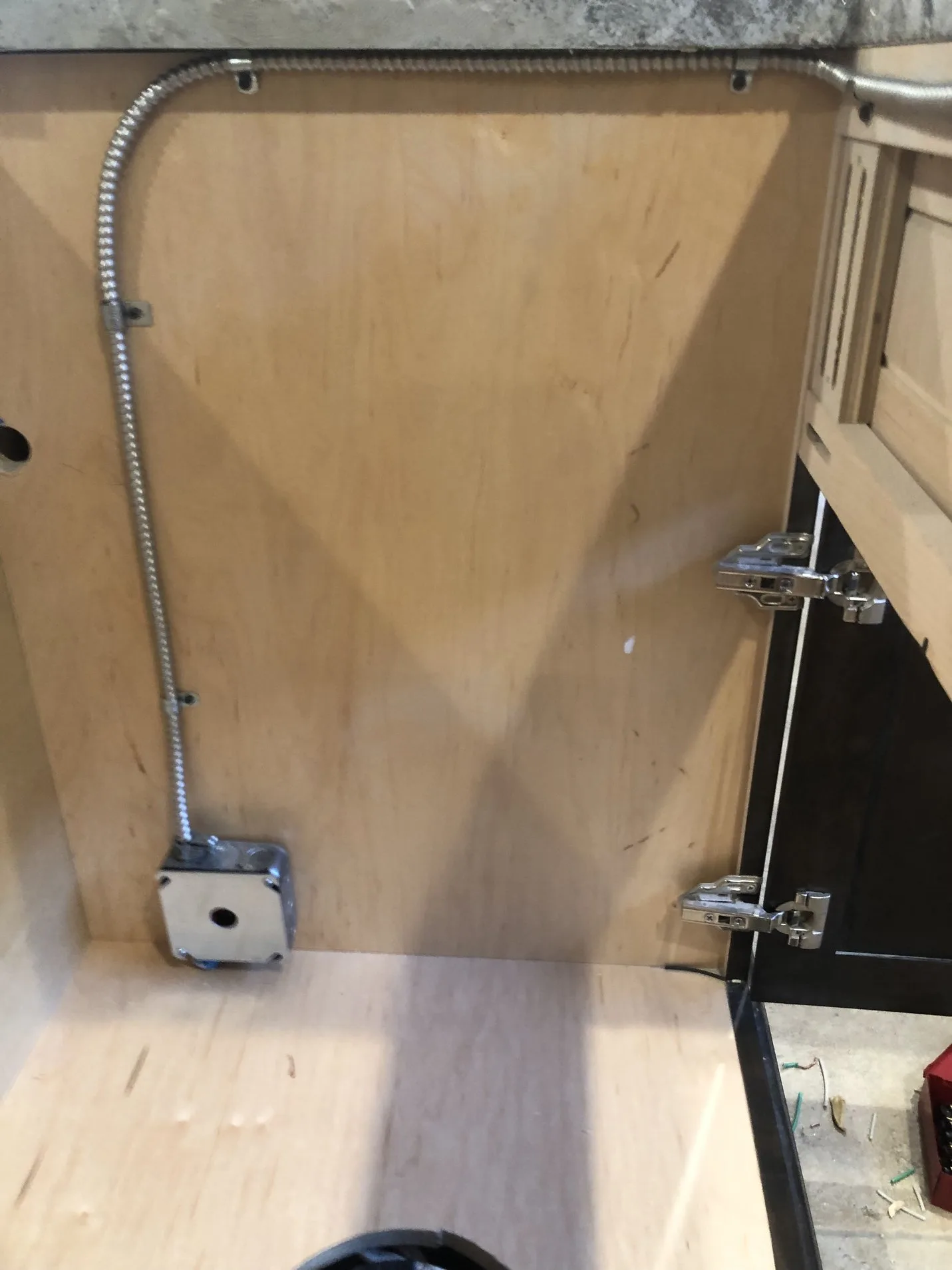 Finished under-counter electrical installation in a kitchen or cabinet area.