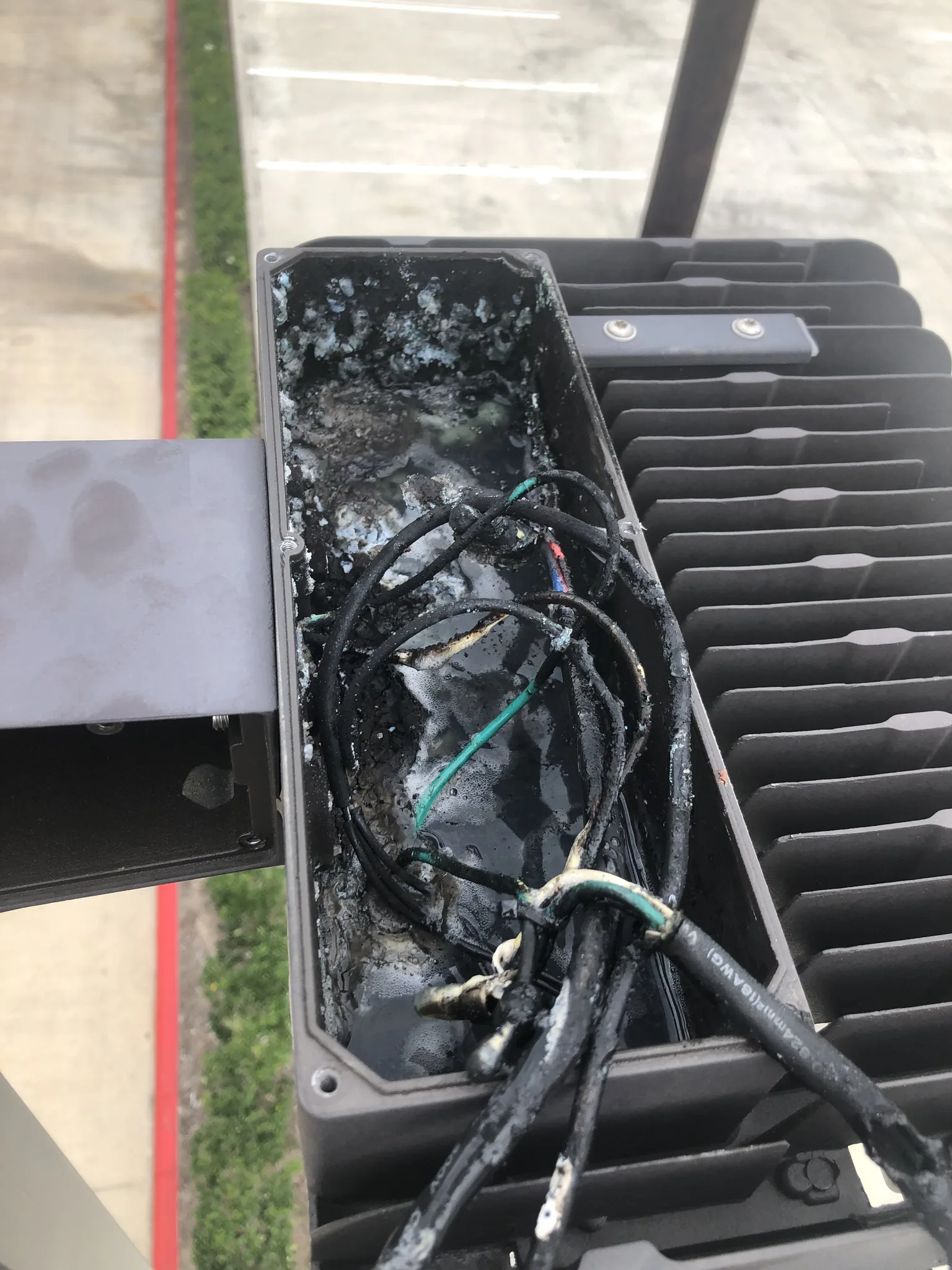 Outdoor lighting housing opened with visible moisture and damaged wiring