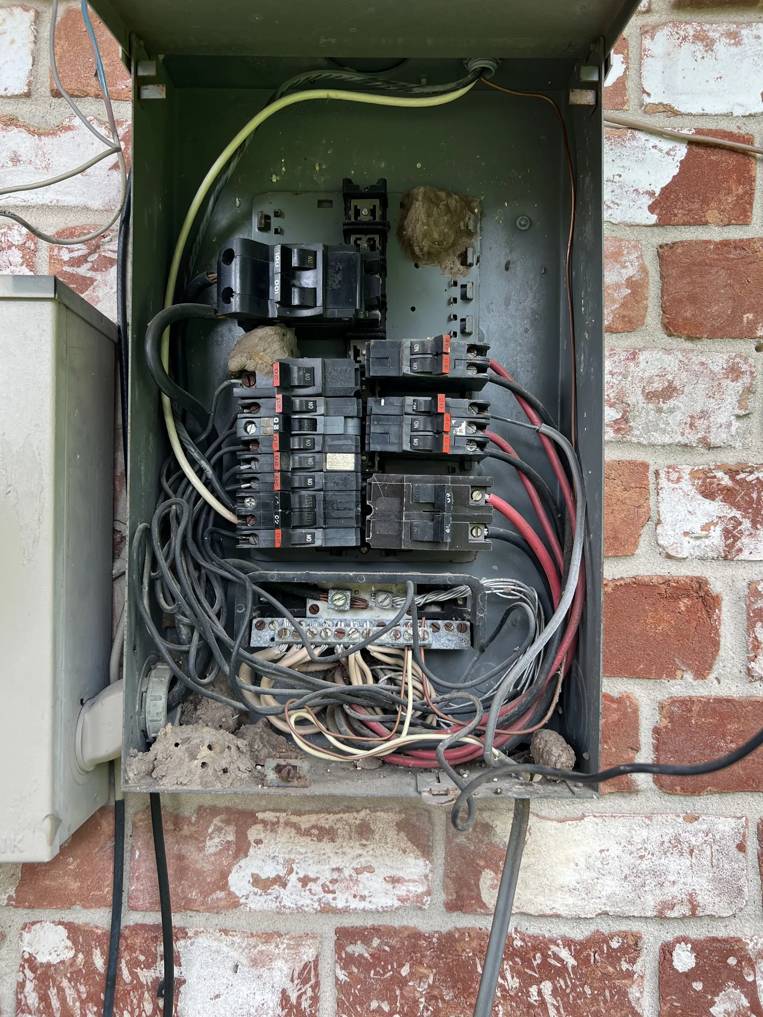 Older exterior electrical panel with breakers and crowded wiring