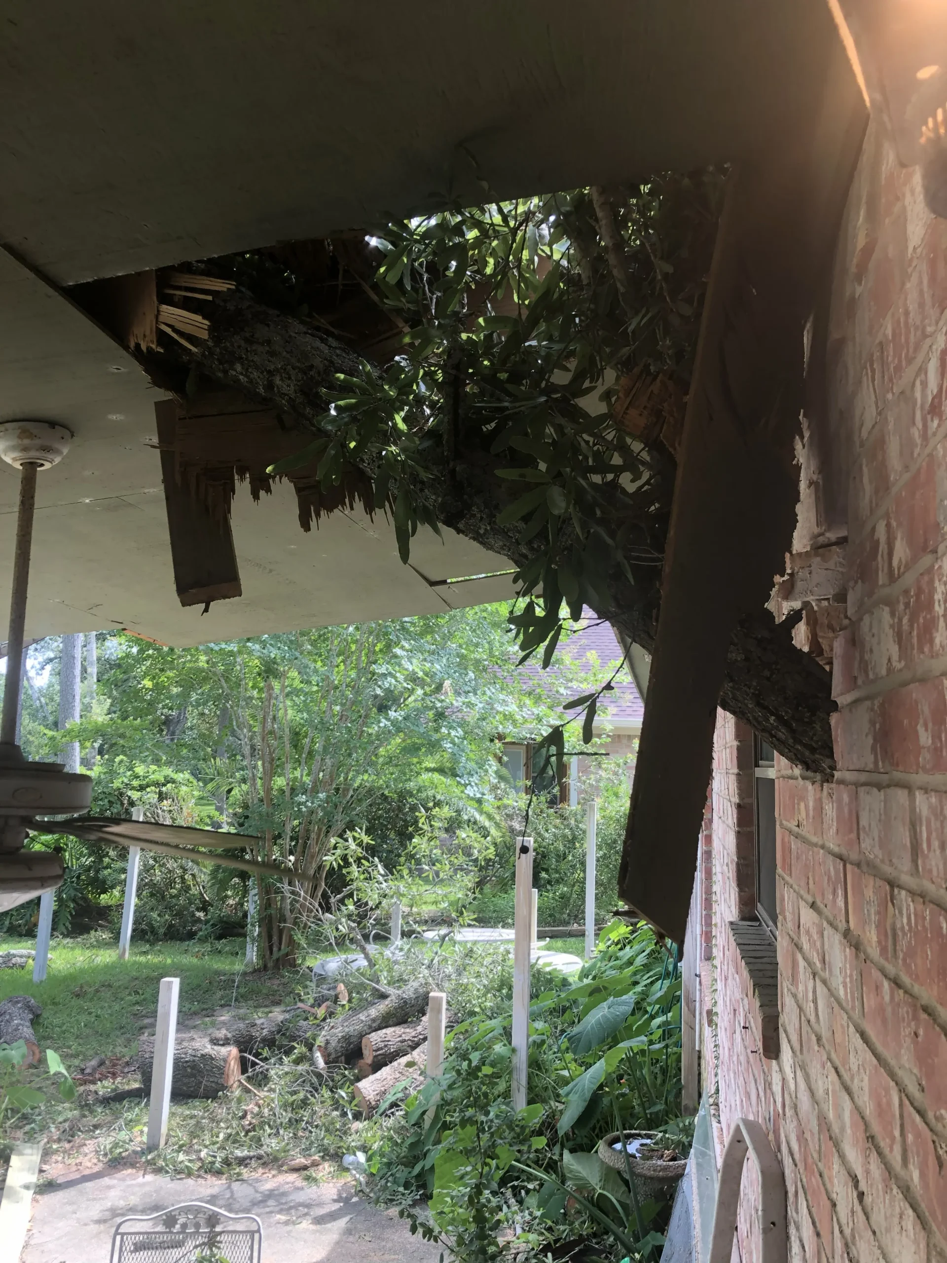 Fallen limb damaging a home exterior near electrical areas