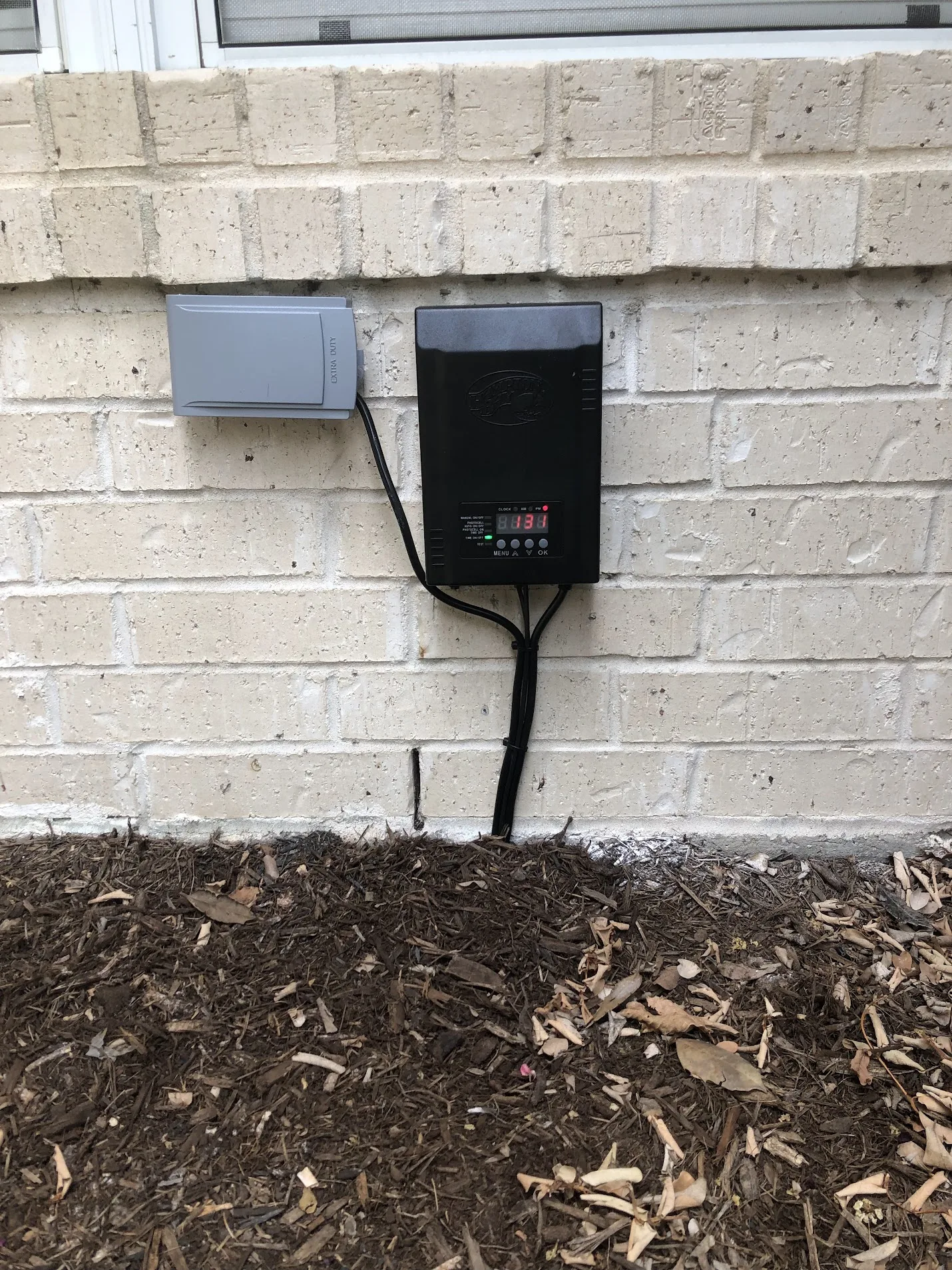 Wall-mounted residential electrical equipment installed on an exterior brick wall.