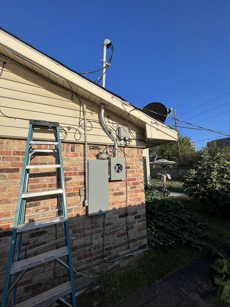 Overhead electrical service equipment being repaired on a Houston-area brick home