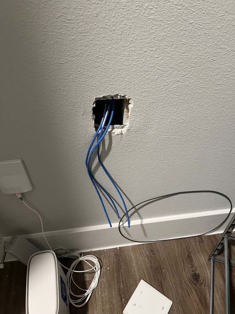 Residential electrical rough-in with wiring coming through a wall opening.